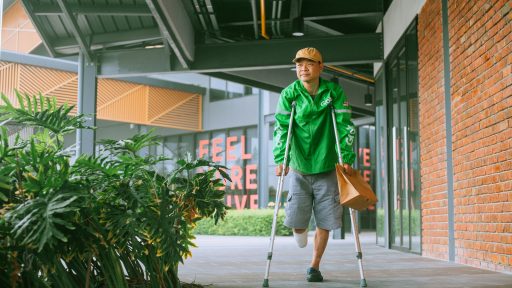 a man with crutches walking down a sidewalk