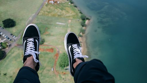 person wearing blue-and-white VANS low-top sneakers with aerial view of body of water