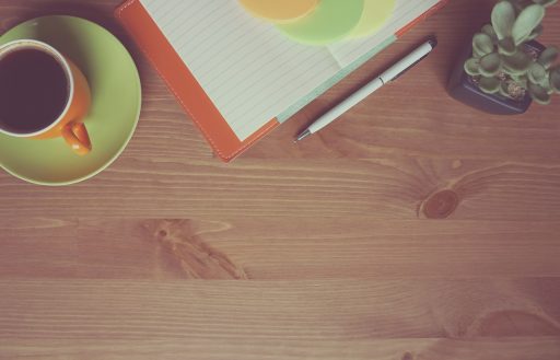 Zzp'er die zijn uurtarief herberekent achter een bureau met een laptop en notitieboek